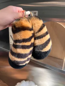 Close-up of plush tiger print tail charms with golden spring ring clasps for bags