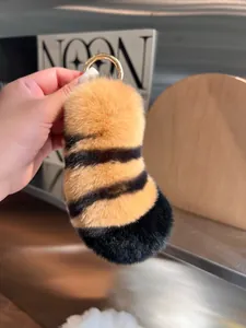 Detail of plush tiger tail keychain with orange stripes and gold metal hook