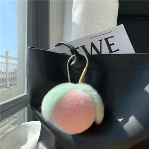 Detail eines rosa Pfirsich-Pelz-Schlüsselanhängers an einer Tasche mit goldener Schnalle
