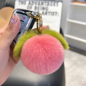 Cute plush peach keychain made of pink rabbit fur with green leaves and gold ring