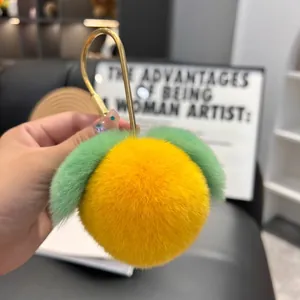 Close-up of a fluffy yellow peach keychain with green leaves and a golden U-shaped hook