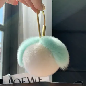 Nahaufnahme von flauschigem mintgrün-weißem Fell-Schlüsselanhänger mit goldenem U-Verschluss