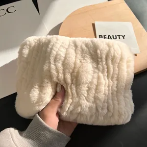 Detail showing plush cream faux fur texture and striped wavy pattern on hand-held pouch