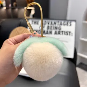 Close-up of a soft plush peach keychain with green leaves and a golden metal clasp