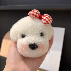 Vue détaillée du charm chiot en peluche blanche avec un nœud décoratif à carreaux rouges