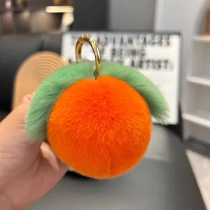 Detail of soft orange plush peach keychain with green leaves and golden metal ring clasp