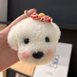 Gros plan du porte-clés chien en peluche blanche avec un nœud à carreaux rouges