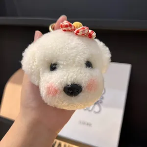 Gros plan d'un porte-clés chien en peluche blanche avec un nœud à carreaux rouges