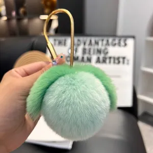 Close-up of mint green rex rabbit fur peach keychain with a large gold circular metal clasp