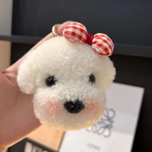 Gros plan d'un porte-clés chien en peluche blanche avec nœud à carreaux rouges