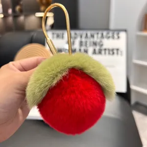 Close-up of red plush peach keychain with soft fur texture and golden metal hook