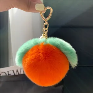 Detail eines flauschigen Pfirsich-Anhängers in Orange mit goldenem Herz-Verschluss