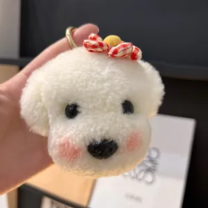 Détail d'un porte-clés chien en peluche blanche avec nœud à carreaux et anneau doré