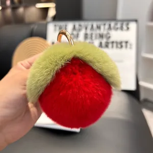 Close-up of soft red plush peach keychain with green leaves and golden clasp