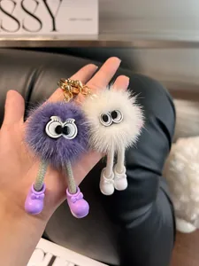 Dettaglio di portachiavi mostro in peluche viola e bianco con gambe lunghe e occhi