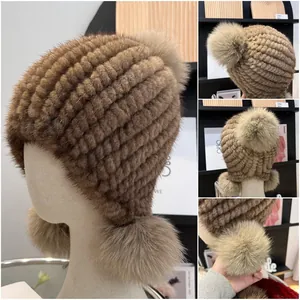 Detailed close-up of brown mink fur knitted hat with three fox fur pom poms and ear protection