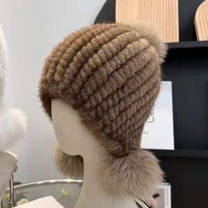 Brown mink fur woven hat with fox fur pom-poms and ear protection on mannequin