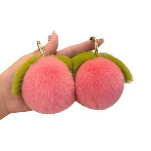 Pink plush peach keychain with faux rabbit fur and green leaves on gold metal ring
