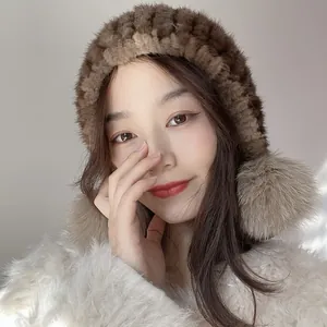 Close-up of a dark brown mink fur hat with fluffy pom-poms and warm winter ear flaps