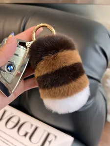 Close-up of fluffy striped rabbit fur keychain with gold ring on a car key