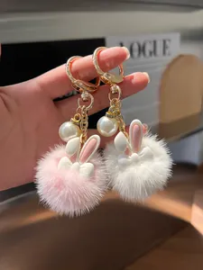Detail of plush mink fur bunny keychain with golden clasp and pearl accent for handbags
