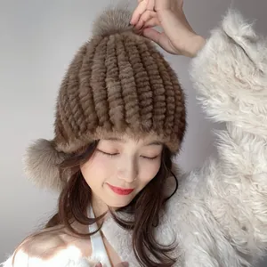 Detailed texture of brown mink fur hat with fluffy fox fur balls and ear protection