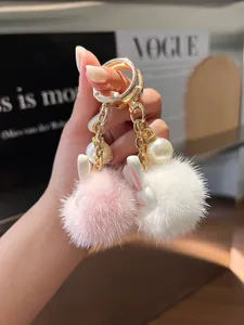 Detail of pink and white plush bunny keychains with gold chains and pearl accents