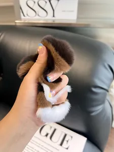 Close-up of a tricolor plush accessory with soft fur texture on a black leather background