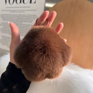 Detail of soft brown faux fur bear paw keychain with metallic circular hook and fluffy texture
