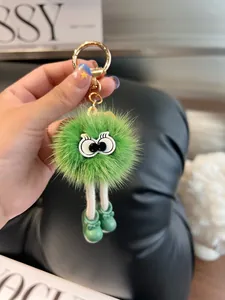 Dettaglio del portachiavi mostro di peluche verde con gambe lunghe e scarpette con fiocco