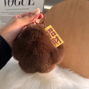 Close-up of fluffy brown rabbit fur paw keychain with a red metal ring held by hand