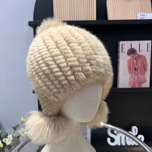 Detail of beige mink fur hat with fox fur pom poms and striped knitted texture for winter