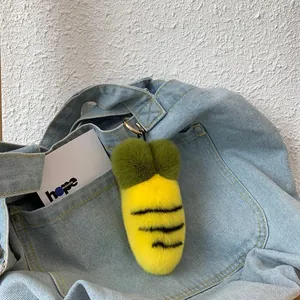 Plush carrot keychain with black stripes hanging on a denim bag as a creative accessory