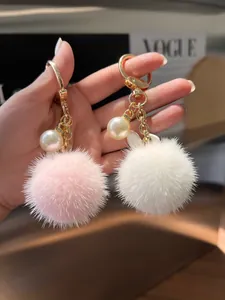 Detailed close-up of fluffy fur bunny keychains in pink and white with gold hardware