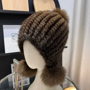 Detail of brown mink fur hat featuring three fluffy fox fur pom-poms and knit texture