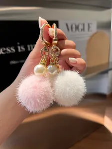 Close-up of pink and white plush bunny keychains with gold hardware and pearl accents