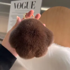 Brown faux rabbit fur paw keychain with gold ring, shown in a stylish fashion lifestyle setting