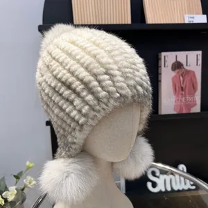 Detail of cream mink fur knitted hat featuring two large matching fluffy pom-poms