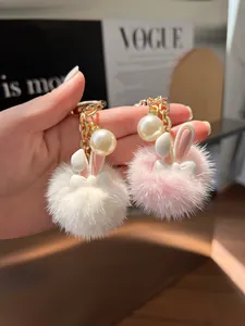 Detailed view of white and pink fluffy bunny keychains with large pearls and gold chain