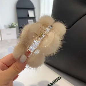 Detailaufnahme der beigen Nerzfell-Pompons an einer bernsteinfarbenen Haarklammer
