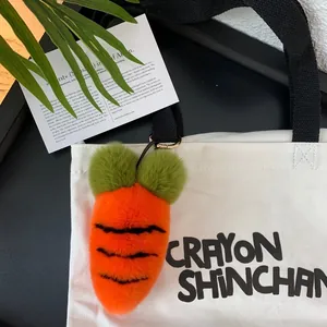 Close-up of fluffy carrot plush keychain with metal ring on a white canvas bag