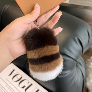 Striped faux rabbit fur plush keychain charm on a mobile phone case against a Vogue magazine