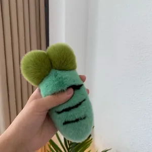 Close-up of mint green plush carrot accessory with soft faux fur texture and green pom-poms