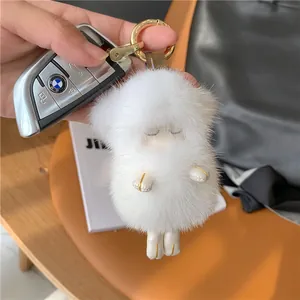 Close-up of fluffy white mink fur sheep doll keychain with a gold ring and sleeping face