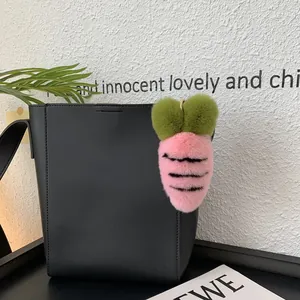 Pink plush carrot bag charm with black stripes and green top on a black tote bag