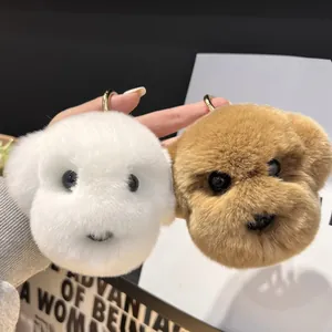 Gros plan de porte-clés chien en peluche blanc et brun avec anneaux dorés