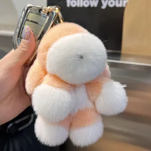 Détail d'un porte-clés chien en peluche orange et blanc fixé à une clé de voiture
