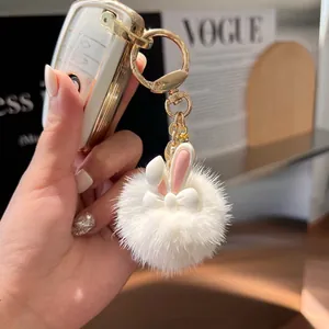 Plush white bunny keychain and golden car key protector on fashion magazine background