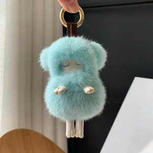 Detail of mint green plush sheep keychain with golden hardware and leather strap