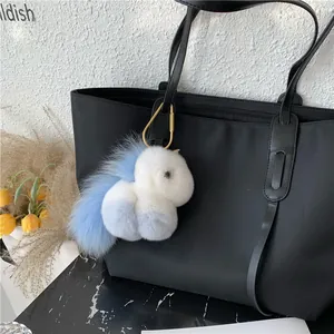 Cute blue and white gradient plush unicorn keychain with gold clasp on a black tote bag
